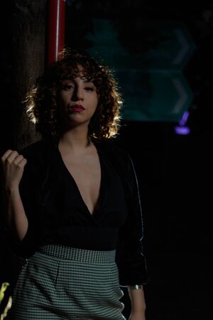 Young girl with curly brown hair, Caucasian skin, red lipstick, black suit and white and black checkered skirt, strolling through the square in the late afternoon and early evening.の写真素材