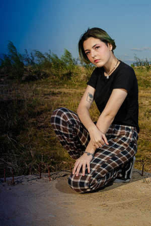 Alternative young girl with green hair in black shirt and checkered pants strolling down the street