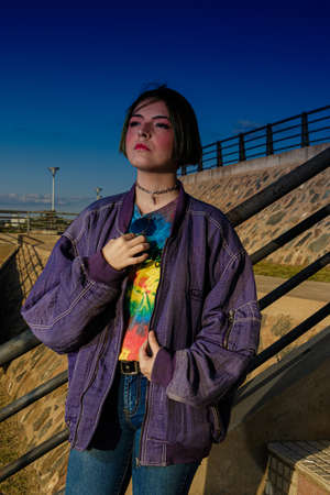 Alternative young girl with green hair in black shirt and checkered pants strolling down the street