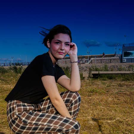 Alternative young girl with green hair in black shirt and checkered pants strolling down the street