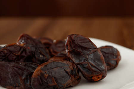 dates without seeds on a white plate the wooden table and unfocused background