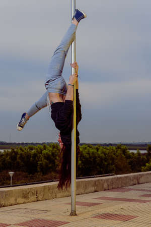 Alternative-looking woman practicing Poledance street on poles in city parksの写真素材