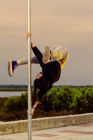 Alternative-looking woman practicing Poledance street on poles in city parksの写真素材