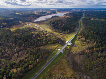 Beautiful aerial view of road bridge over the river surrounded by forest. The Republic of Karelia. On the bridge one lane in each direction. Behind him one can see meadows, lakes and fields. On the sky clouds float. Russia, 2016の写真素材