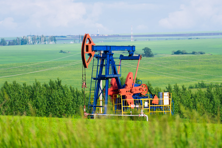 working oil pump on the ground among the green fieldsの写真素材