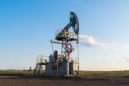 working oil pump on the ground among the green fieldsの写真素材