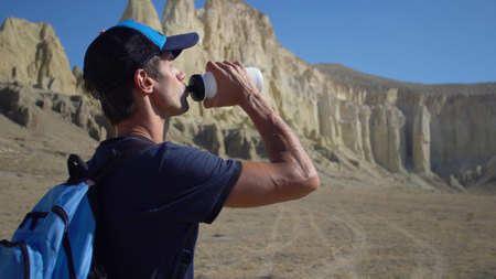 A young traveler drinks water against the rocksの写真素材