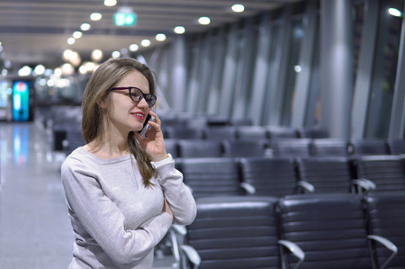 Young, beautiful girl talking on the phone in an empty airport terminalの写真素材