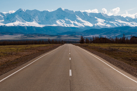 empty highway leading to the mountains with snow caps. Altai mountains landscapeの写真素材