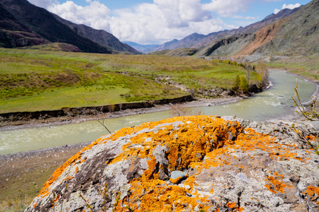 unusual stone formations with colored patches of lichen and moss on the background of mountains and riverの写真素材