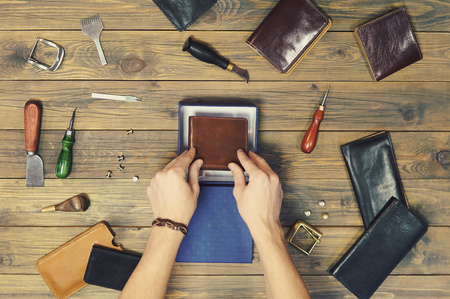 hands put a new leather wallet in a gift box. conceptual image of a gift to a man. composition of...