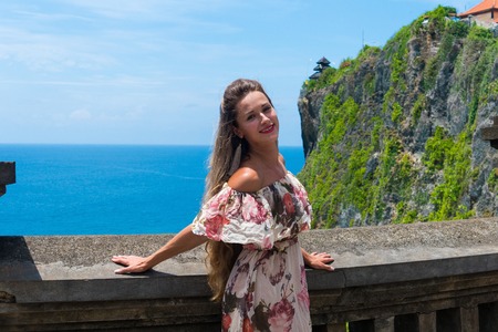 Traveller girl enjoy amazing view one of the most popular tourist attractions island Bali balinese hindu Uluwatu Temple, Indonesiaの写真素材