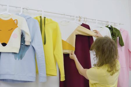 Female fashion designer works on new womenswear collection for clients workshop studio, dressmaker, tailor or needlewoman standing near clothing rack with fashionable stylish handmade clothesの写真素材
