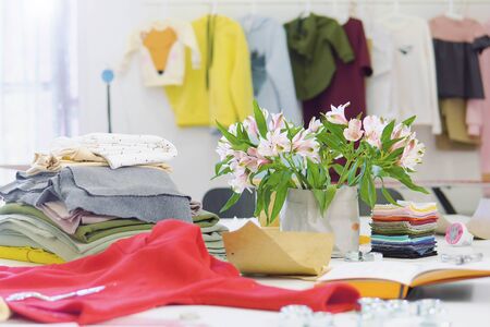 Creative fashion designer desk or workplace with sewing equipment, fabrics, templates, modern stylist inspirational office, dressmaker atelier with clothes on hangers, couturier showroomの写真素材