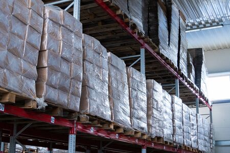 storage warehouse and racks on which there are cardboard boxes with finished productsの写真素材