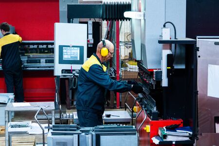 Worker operator bending metal sheet process by sheet bending machine for bus manufactuing part, steel folding with machineの写真素材