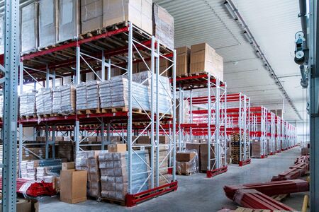 storage warehouse and racks on which there are cardboard boxes with finished productsの写真素材
