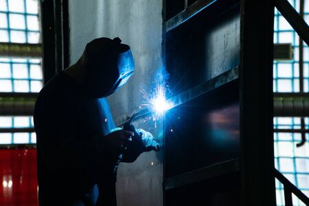 Welder in his workshop welding metal, lots of sparks flying aroundの写真素材