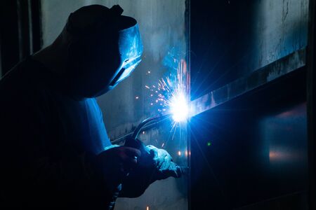 Welder in his workshop welding metal, lots of sparks flying aroundの写真素材