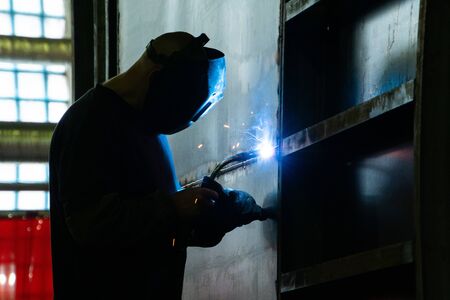 Welder in his workshop welding metal, lots of sparks flying aroundの写真素材