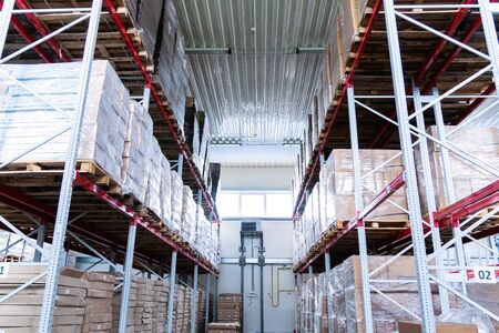 storage warehouse and racks on which there are cardboard boxes with finished productsの写真素材