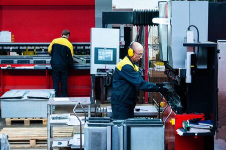 Worker operator bending metal sheet process by sheet bending machine for bus manufactuing part, steel folding with machineの写真素材
