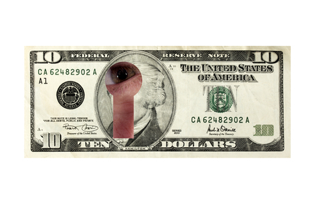 The eye looks through a keyhole cut-out in the tenner.の写真素材
