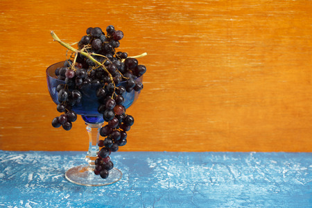 Wooden background with dark grapes in a glass bowlの写真素材