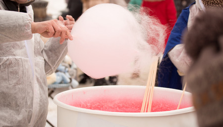 Pink cotton candy. Salesman are spinning the color of sugar with a spinning step. Sweet taste by food machine processの写真素材