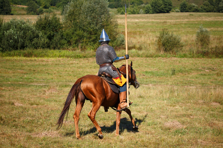 Reconstruction. Medieval armored knight whith lance on horse. Equestrian soldier in historical...