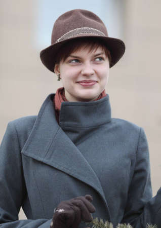 young smiling beautiful girl in gray coat and brown hatの写真素材