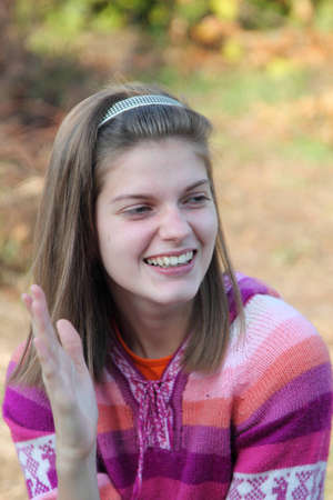 smiling young girl in colourful shirt with  a gesture of raised handの写真素材