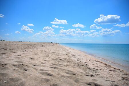 Beautiful sandy beach on a sunny day. Sandy beach with blue sky, puffy clouds, and footprints in the sandの写真素材