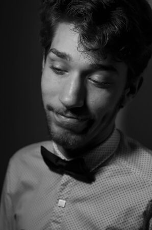 black and white portrait of a cheerful young man with a beard in a white shirt and bow tie. Studio photographyの写真素材