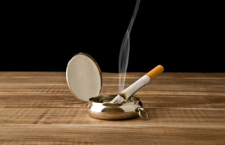 cigarette in an ash-tray on a black backgroundの写真素材