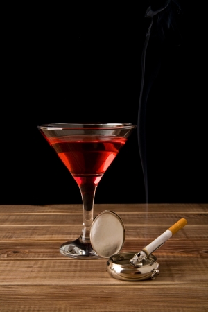 cigarette in an ash-tray and glass of wine on a black backgroundの写真素材