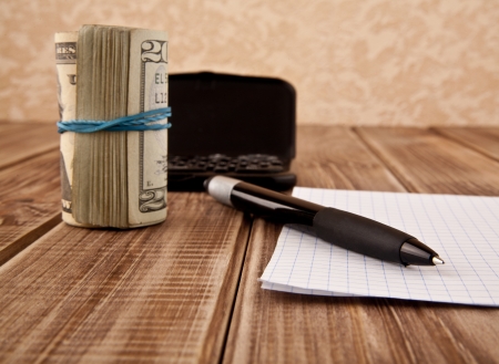 dollars,paper and a pen on a wooden tableの写真素材