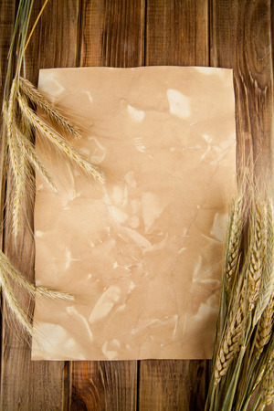 ears of corn of wheat on old paper and wooden tableの写真素材