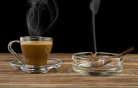 cup coffee and cigarette on a wooden tableの写真素材