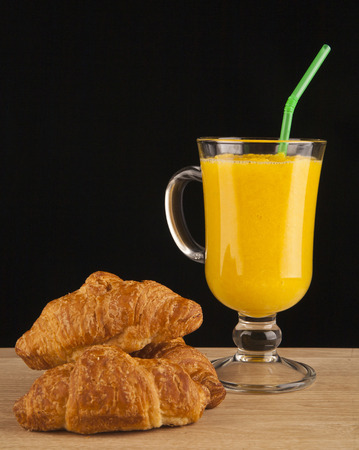 orange juice and croissants on a black backgroundの写真素材