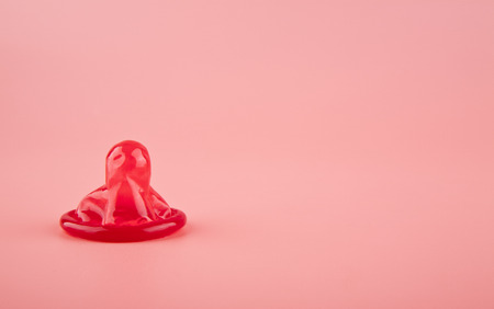 red condom on a pink background close upの写真素材