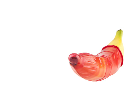 red condom and a banana isolated on white background closeupの写真素材