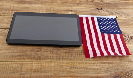 black tablet and a USA flag on wooden backgroundの写真素材