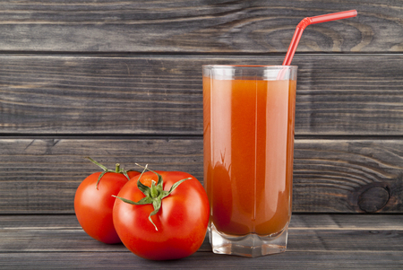 red, juicy, fresh tomatoes and juice on a wooden backgroundの写真素材