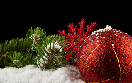 branch of a Christmas tree, gifts and a snowflake in the snow on a black background close-upの写真素材