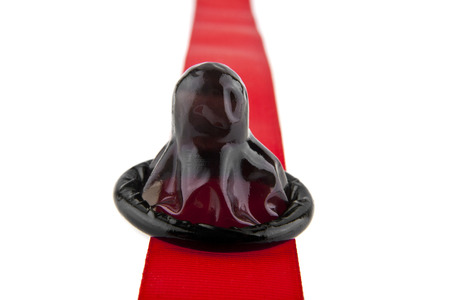 red tape and condom isolated on white background close-upの写真素材