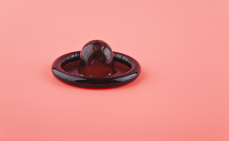 black condom on pink background closeupの写真素材