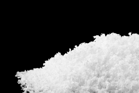 pile of white snow isolated on black backgroundの写真素材