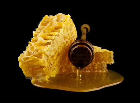 Honeycomb with honey spoon isolated on black background, bee natural ingredients conceptの写真素材