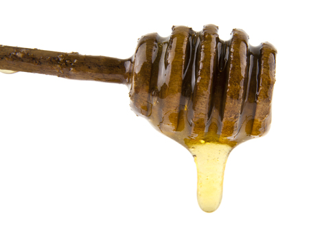 Honey flowing from wooden spoon isolated on whiteの写真素材